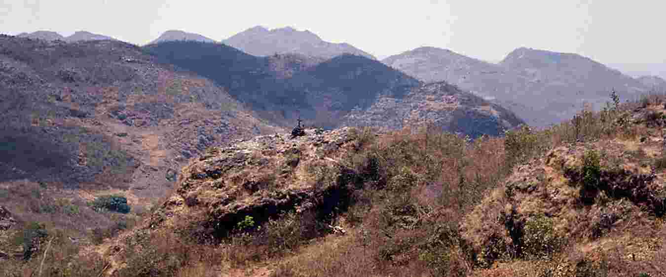 Figure 1.14. Cross shrine on a rock outcrop on the outskirts of the aldea of Canquintic (k’ankintik, meaning unknown), municipio of Nentón. May 1965. A woman in a red huipil kneels to the left of the cross. Entering the village with a loaded mule, I was hailed by a woman who ran from her house to ask “Tas ha chonho’?,” What are you selling? Photo by the author.