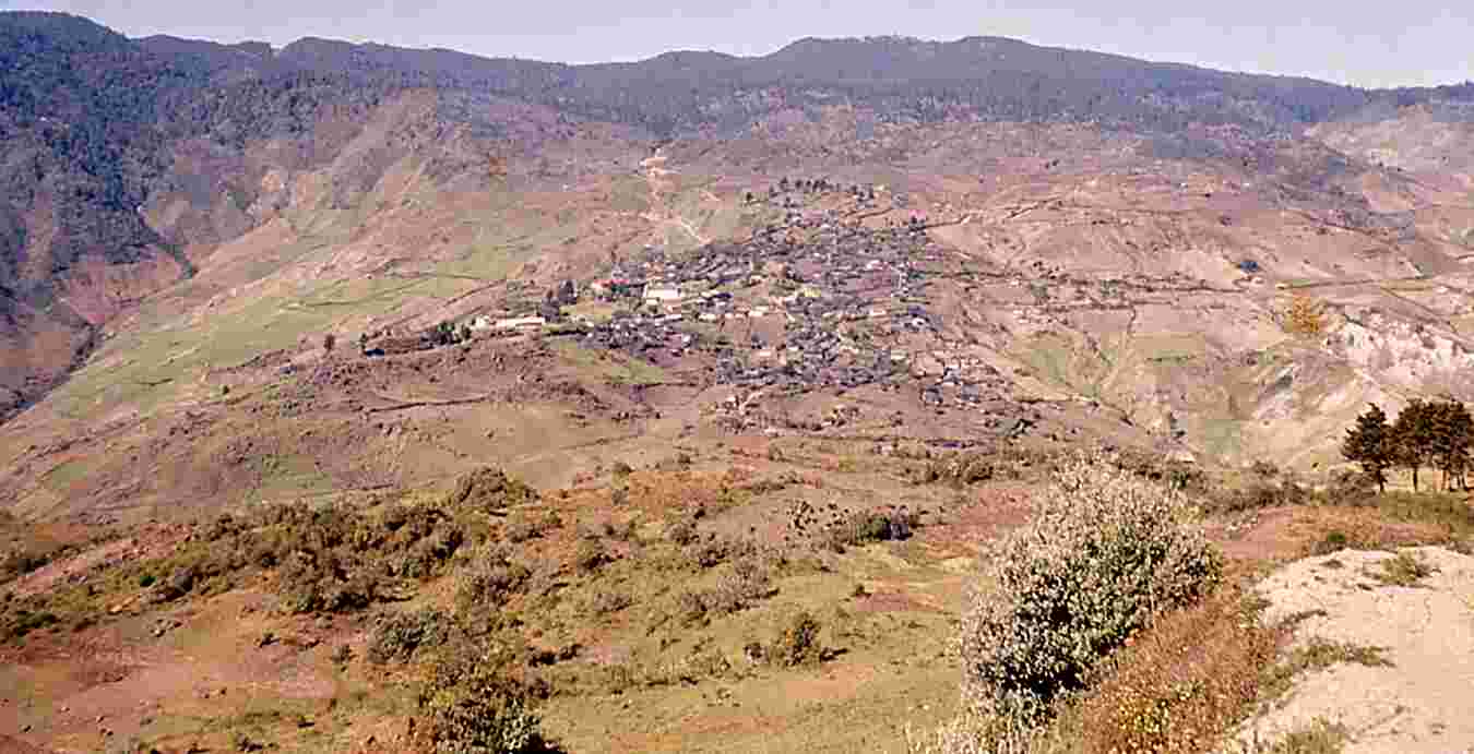 Figure 1.8. San Mateo Ixtatán (ko chonhab’, “our town”), seen across the valley from the road to Barillas. August 1964. Photo by author. The road from Huehuetenango is visible above the town. Below it, the church, and to the left the school and the precolumbian ruins of Guaxaclajún (Wajxaklajunh, “eighteen”).The salt mines lie below the town, above the (unseen) river.