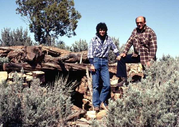 Four people standing above a pithouse looking at the floor and associated floor features