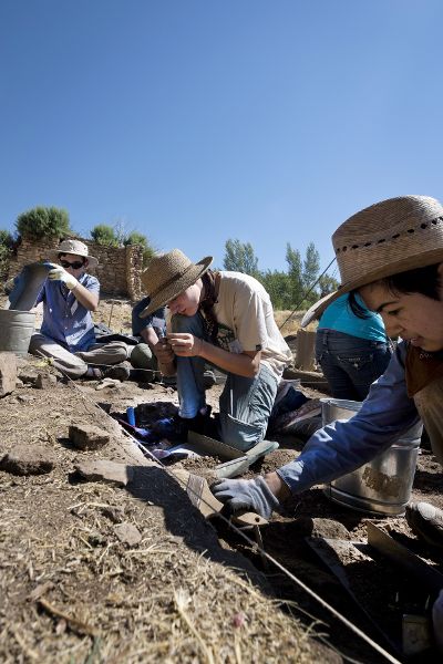 Students participating in field excavation at the Haynie Site in southwest Colorado. People crouch over the earth